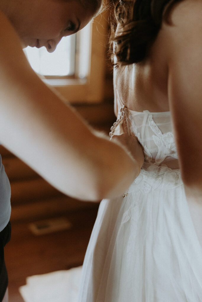 Mother of the bride helping her with the wedding dress