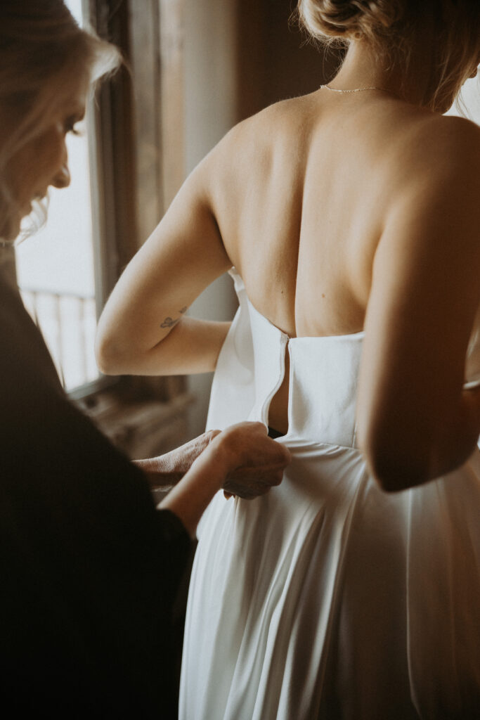 Mother of the bride helping the bride with her wedding dress