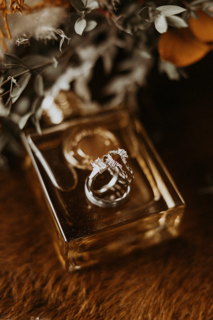 stunning closeup shot of the wedding rings and the perfume the bride used for her ceremony