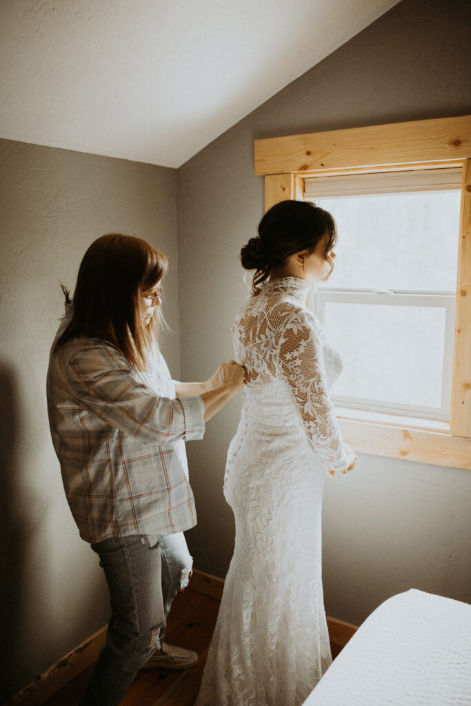 mother of the bride helping her with the wedding dress