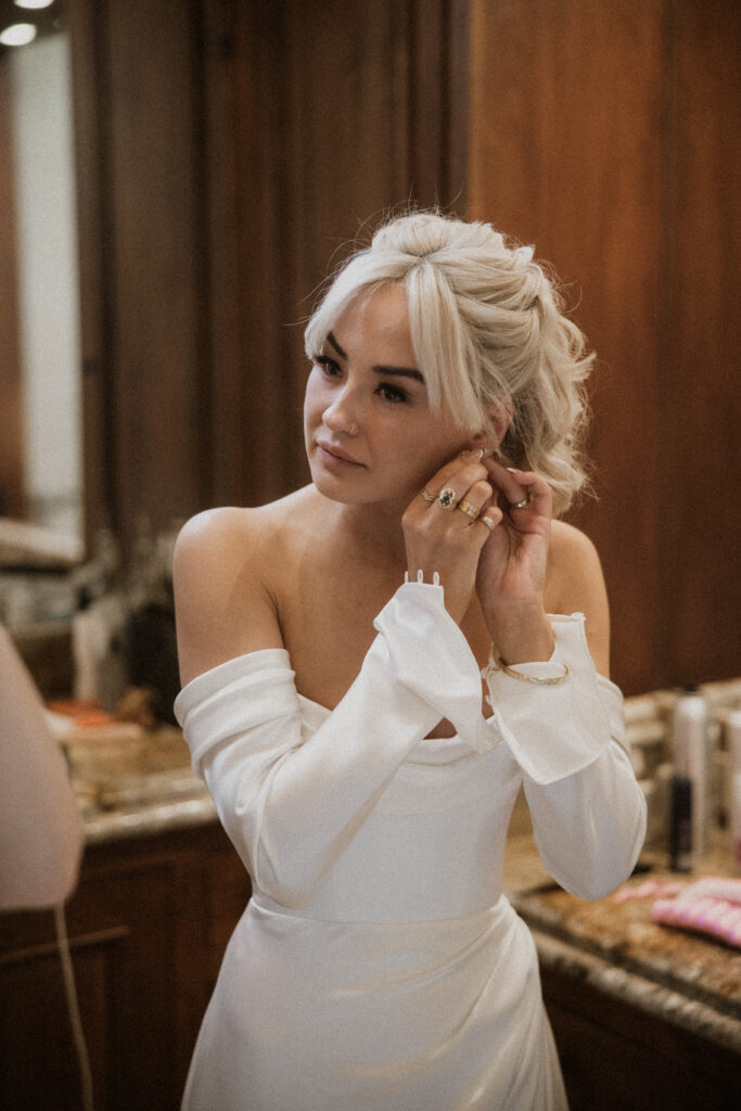 bride putting on her jewelry before the ceremony