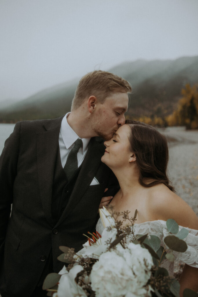 Groom, kissing the bride on the forehead